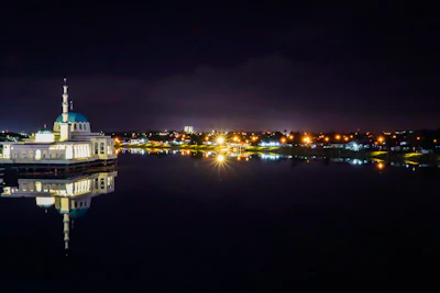 A serene night view of the illuminated mosque with a family silhouette.