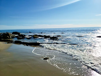 A serene beach scene with soft waves gently lapping against smooth stones.