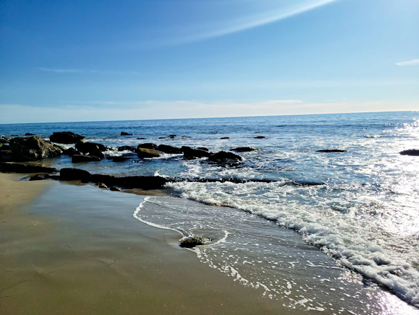 A serene beach scene with soft waves gently lapping against smooth stones.