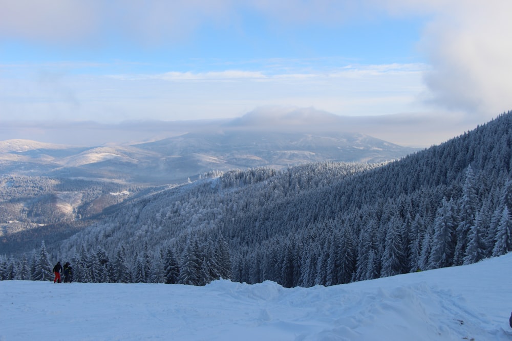 a couple of people standing on top of a snow covered slope