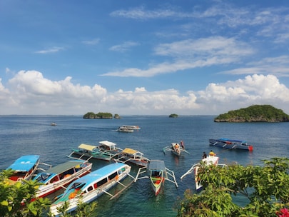 A colorful boat sailing near a tropical island coastline under a bright sky.