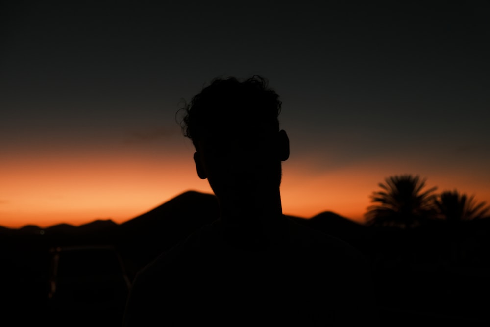 a silhouette of a man with a sunset in the background