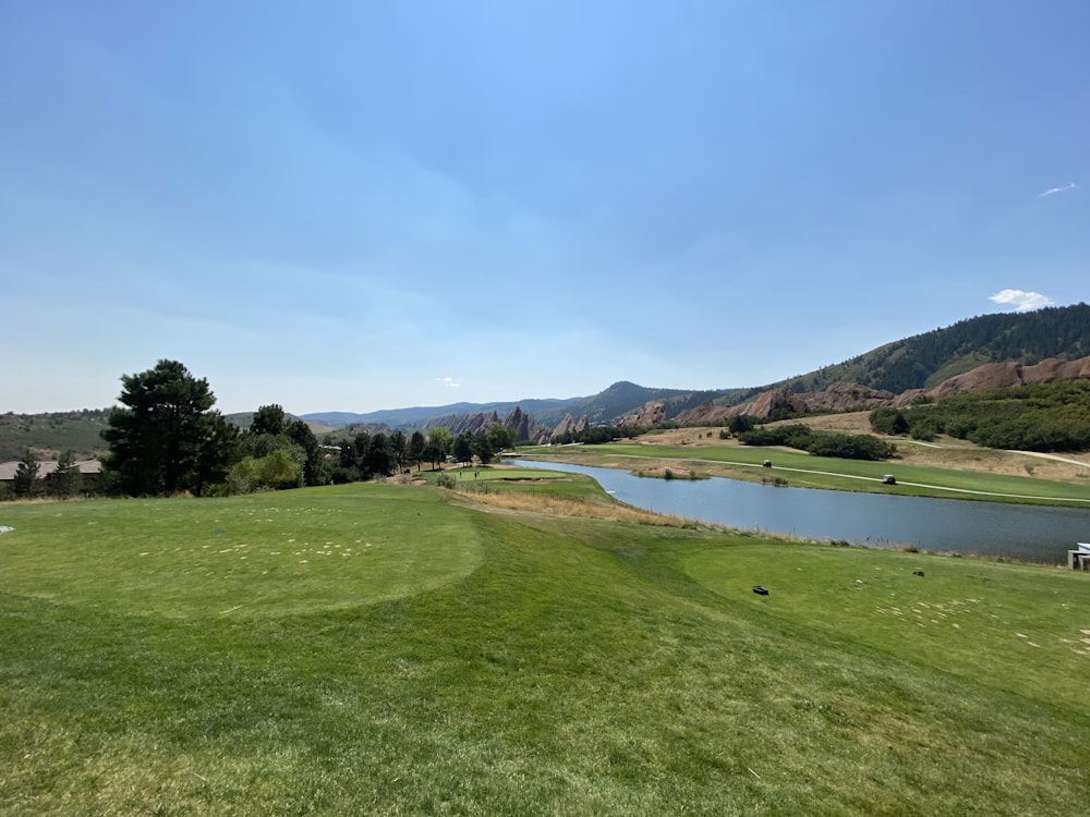 a view of a golf course with a lake and mountains in the background