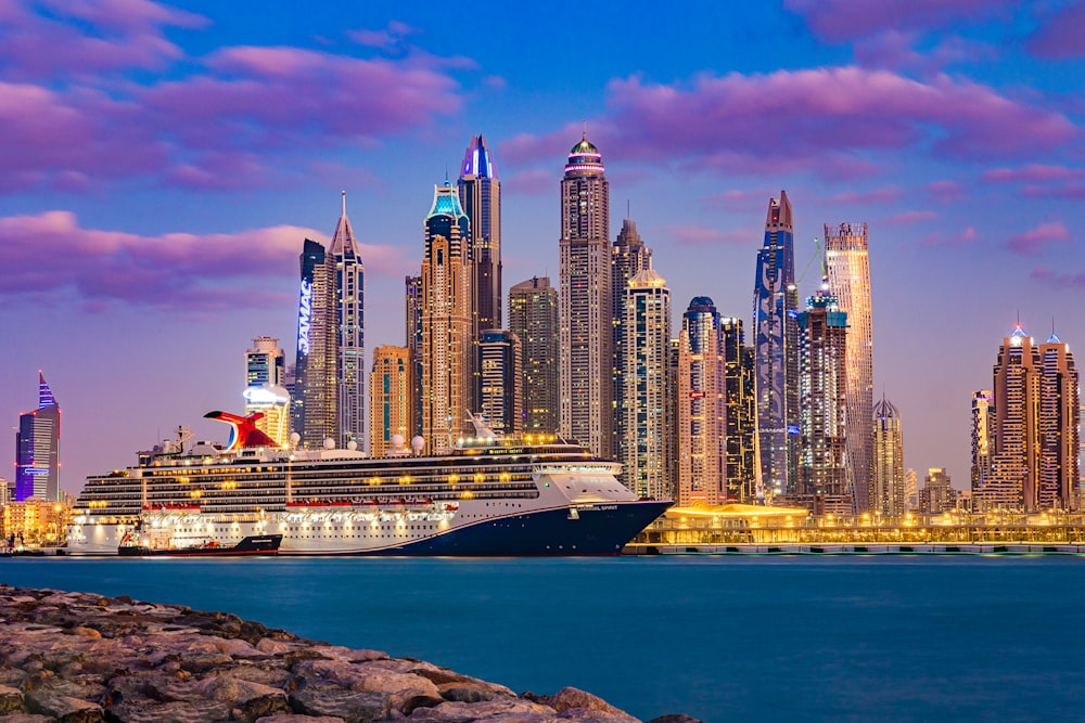 a large cruise ship in front of a city skyline