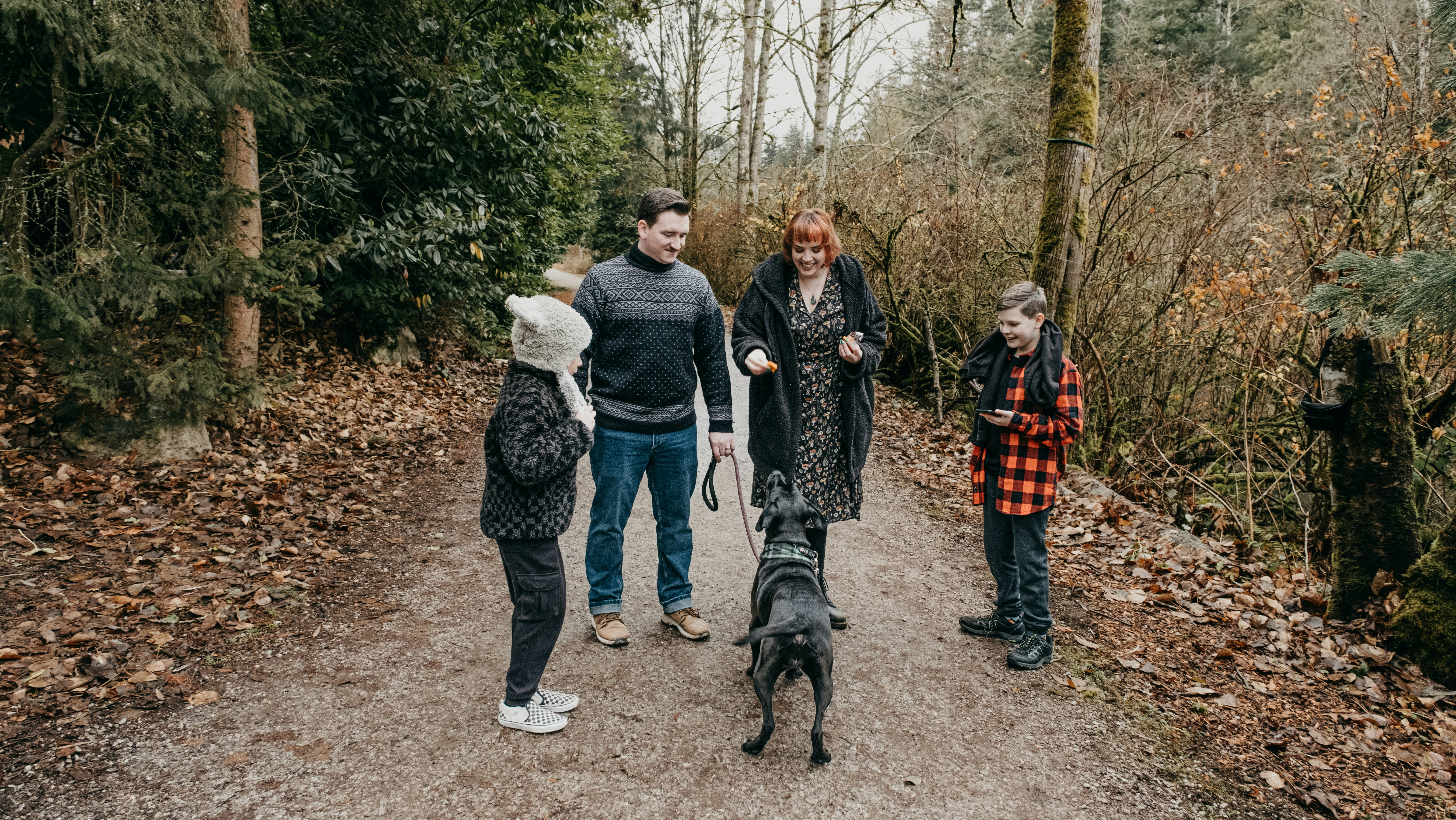 a group of people walking a dog down a dirt road