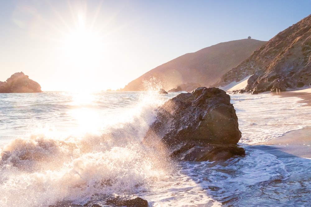 the sun is shining over the water and rocks