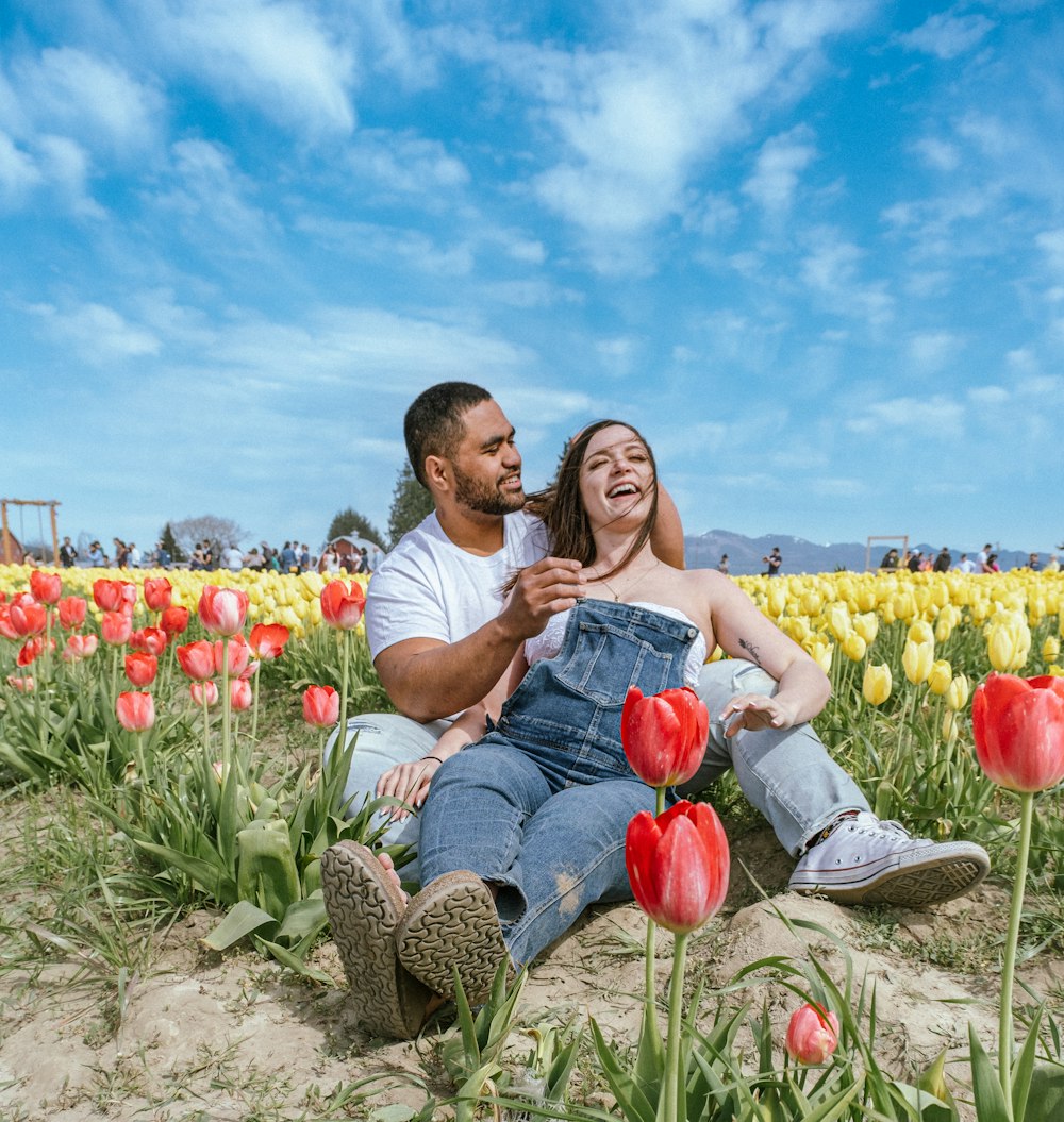 a man and a woman sitting in a field of tulips