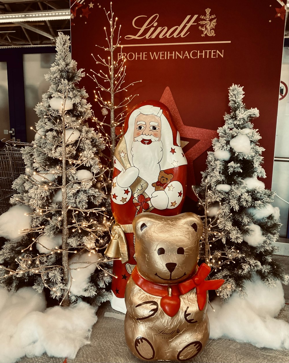 a statue of santa claus and a teddy bear in front of a christmas tree