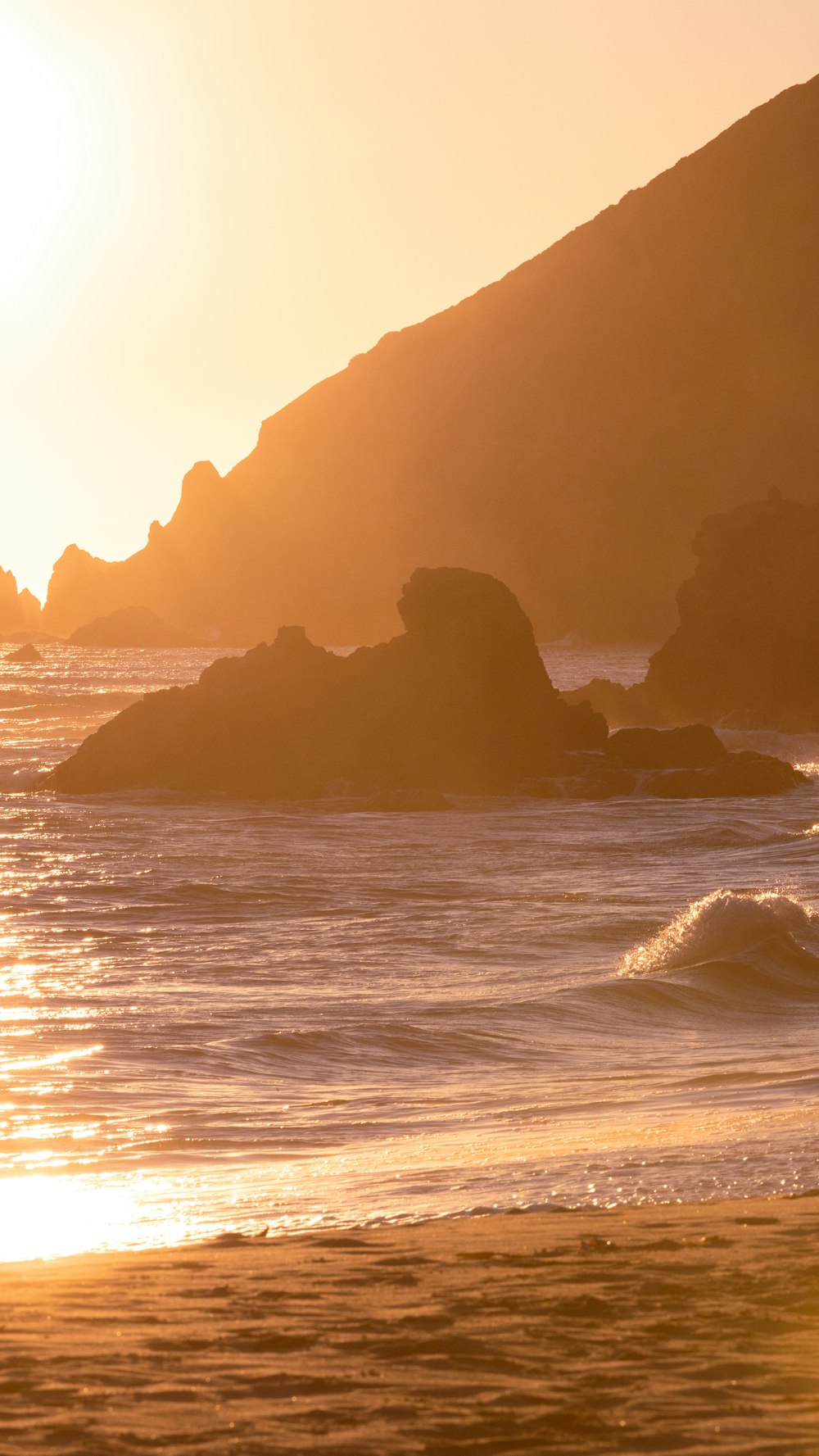 a person walking on the beach at sunset