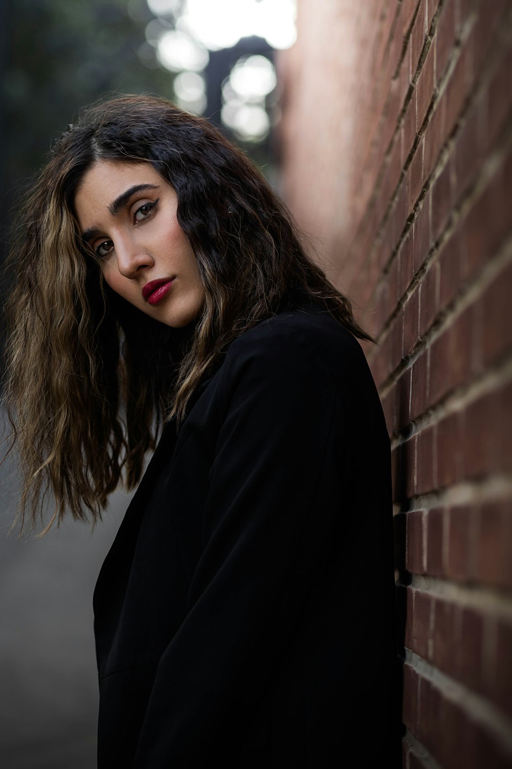 a woman leaning against a brick wall