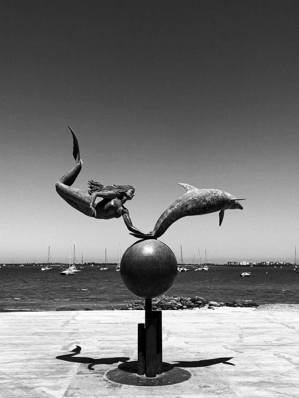 a black and white photo of a statue of a mermaid and a dolphin