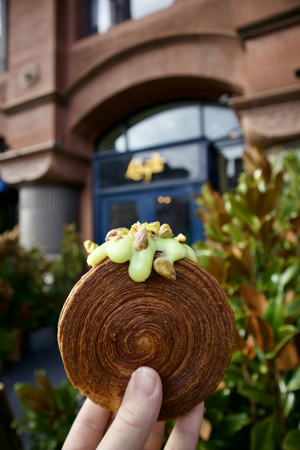 a person holding up a piece of food in front of a building