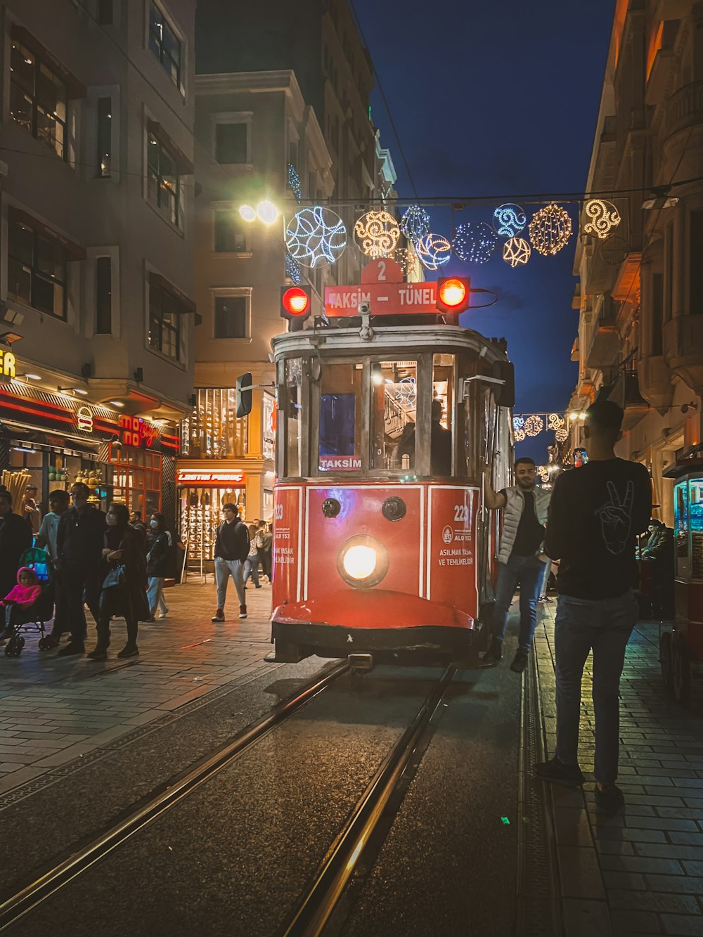 a red trolley car traveling down a street at night