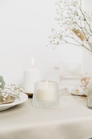 a table topped with a vase filled with flowers and a candle
