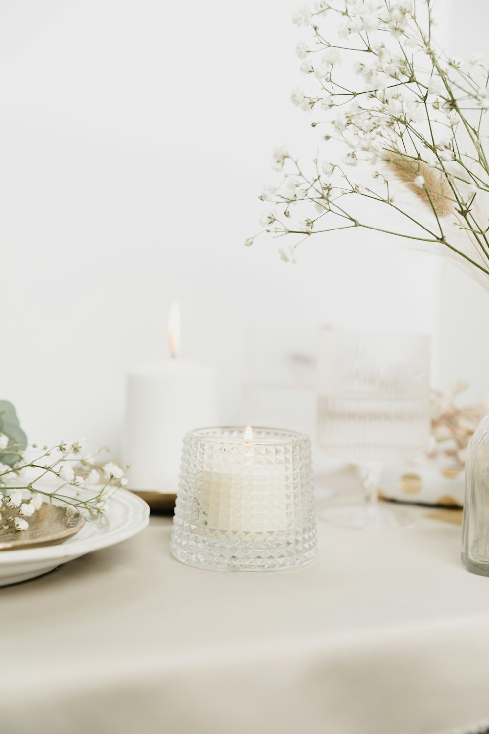 a table topped with a vase filled with flowers and a candle