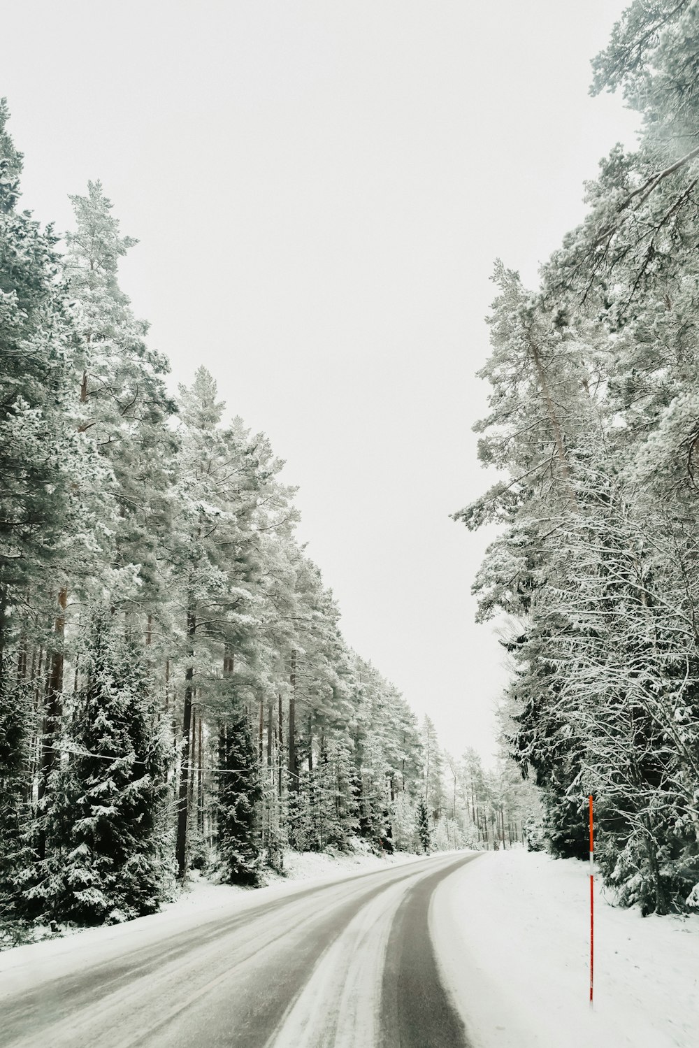 a snowy road with a red sign on the side of it