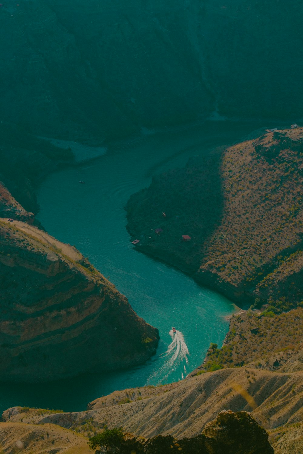 a boat traveling down a river surrounded by mountains