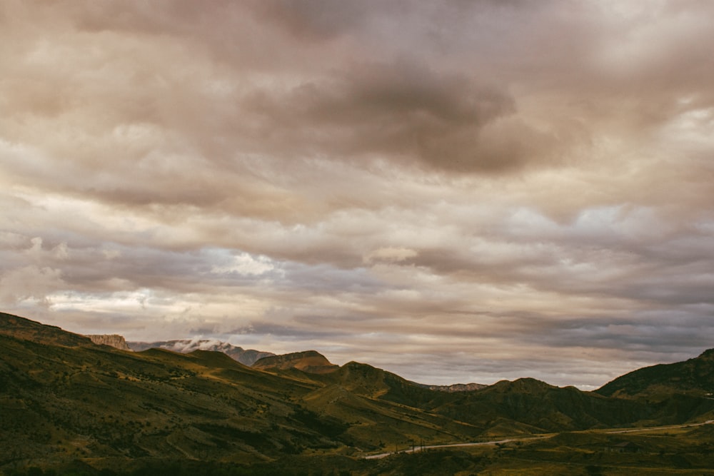 a cloudy sky over a valley with mountains in the background