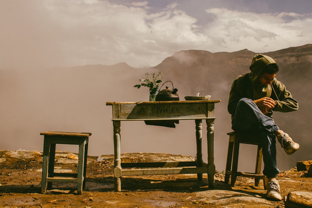 a man sitting at a table on top of a mountain