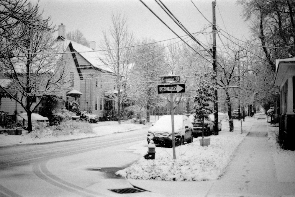 a snow covered street with a street sign in the foreground