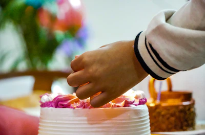 A joyful gathering around the custom cake bar, with hands reaching for little aroma cakes adorned with fresh berries and sprinkles.