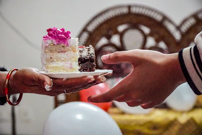A smiling volunteer handing a cake to a grateful recipient in a bright, welcoming setting.