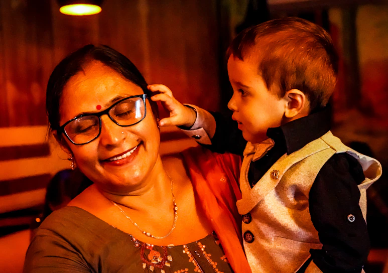 A warm, softly lit photo of Dr. Rosita gently examining a smiling toddler's eyes in a cozy clinic room.