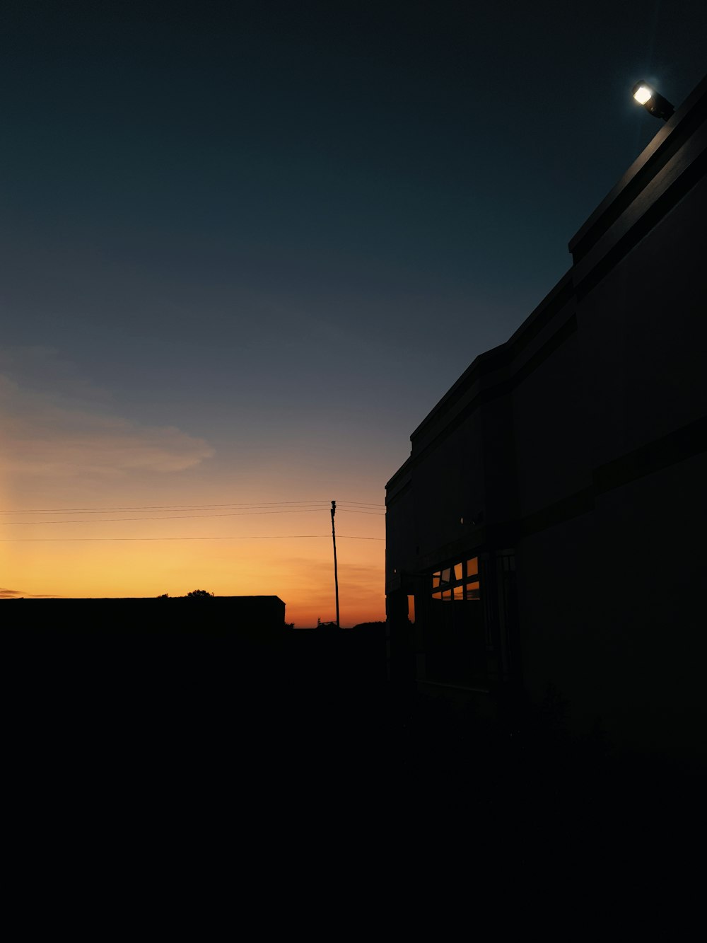 the sun is setting behind a building with a train on it