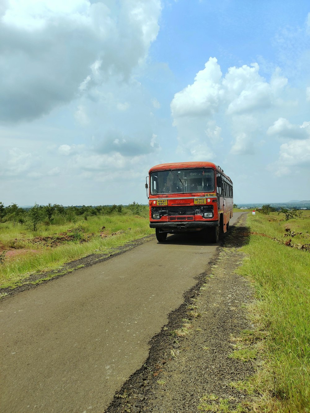 a red bus driving down a dirt road