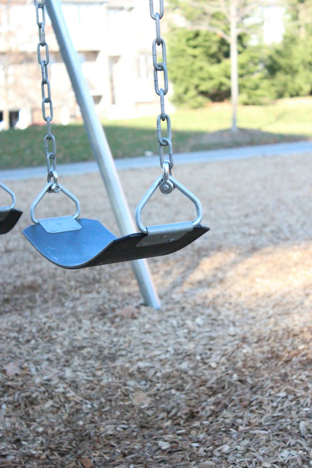 a swing set in a park with a building in the background