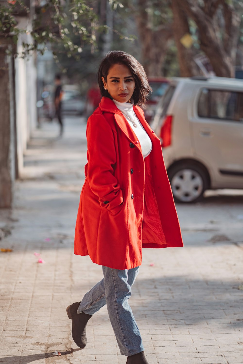 a woman in a red coat is walking down the street