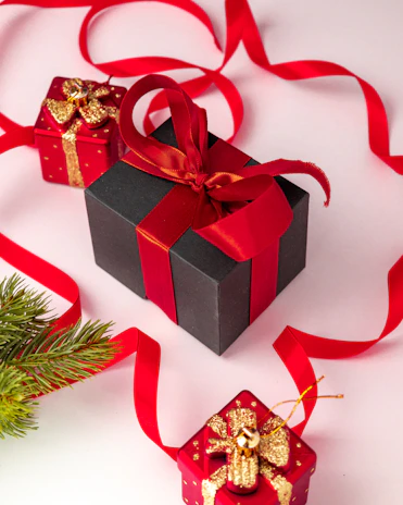 Happy business team exchanging premium corporate gift hampers in a modern office setting with red and black decor accents.