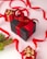 A collection of neatly wrapped gift boxes in various sizes, predominantly featuring red and black wrapping paired with gold accents and ribbons. A black box with a red ribbon is placed centrally, accompanied by smaller red boxes adorned with golden decorations. Bright red ribbon loops artistically across the background, and a sprig of evergreen adds a festive touch.