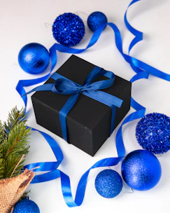 A luxurious black and gold gift basket filled with premium treats and ribbon-wrapped with a gold bow.