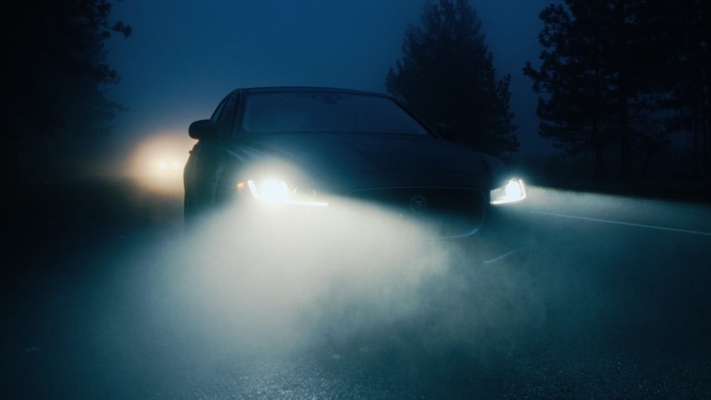 a car driving through a foggy road at night