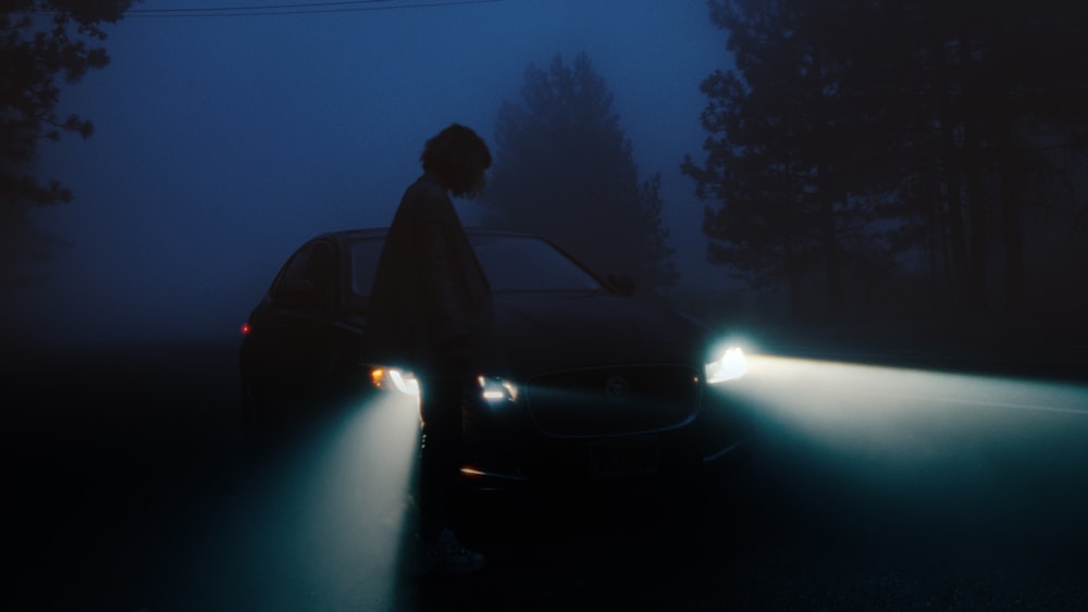 a person standing next to a car in the dark