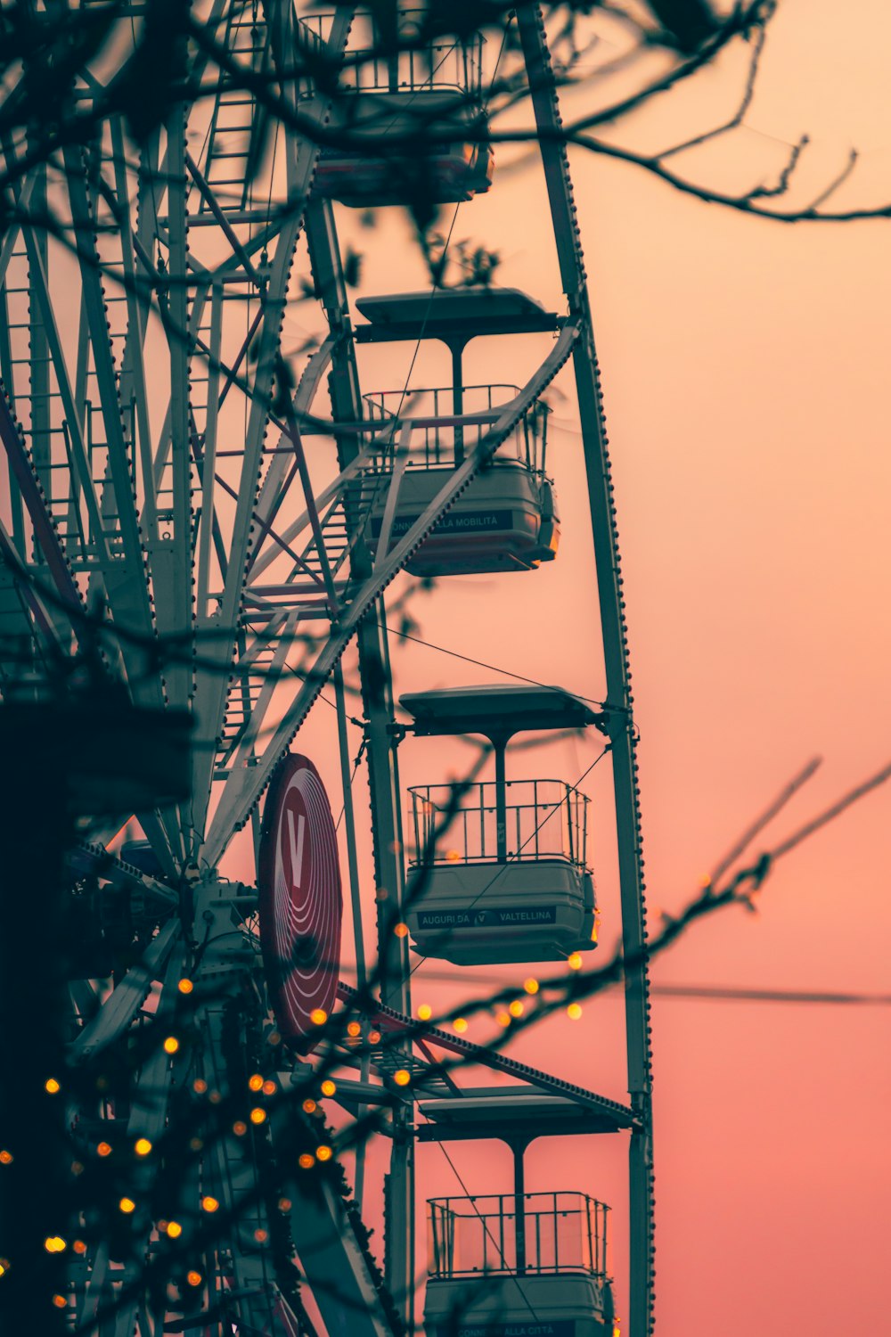 a ferris wheel with lights in the foreground and a pink sky in the background