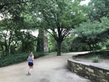 A candid moment of a woman jogging through a leafy neighborhood path.