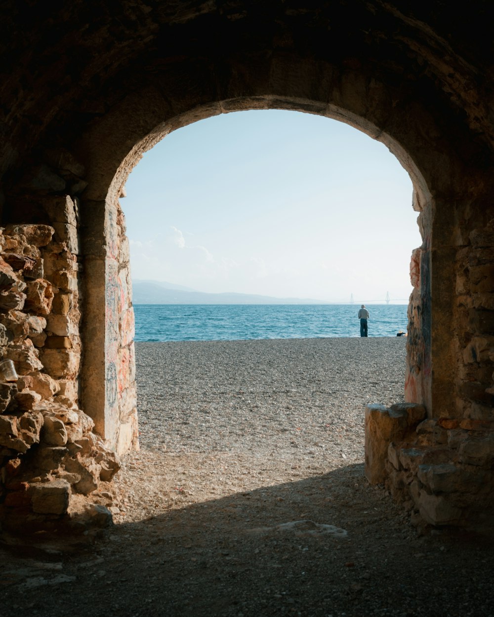 uma pessoa em pé em um arco em uma praia