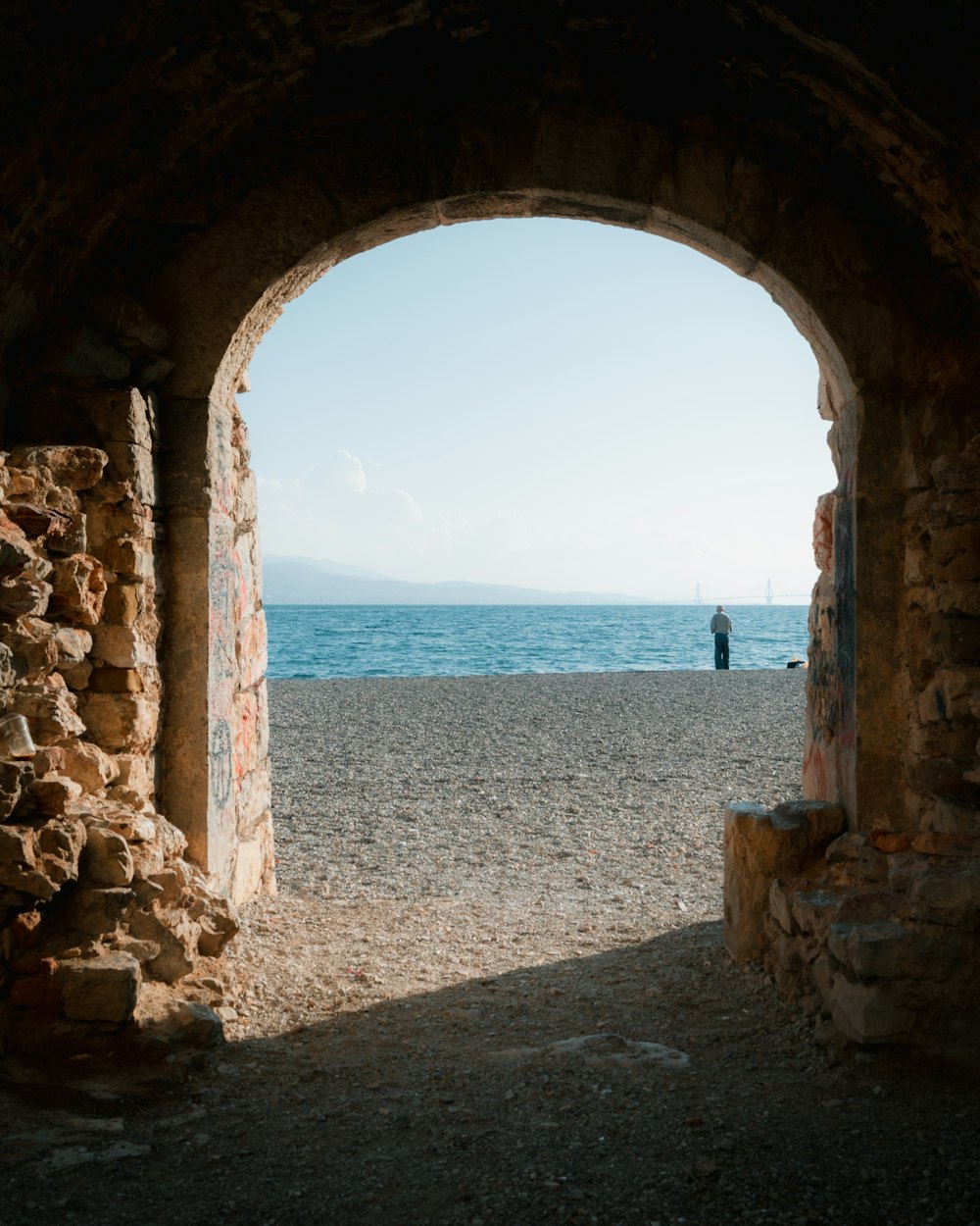a person standing in an archway on a beach