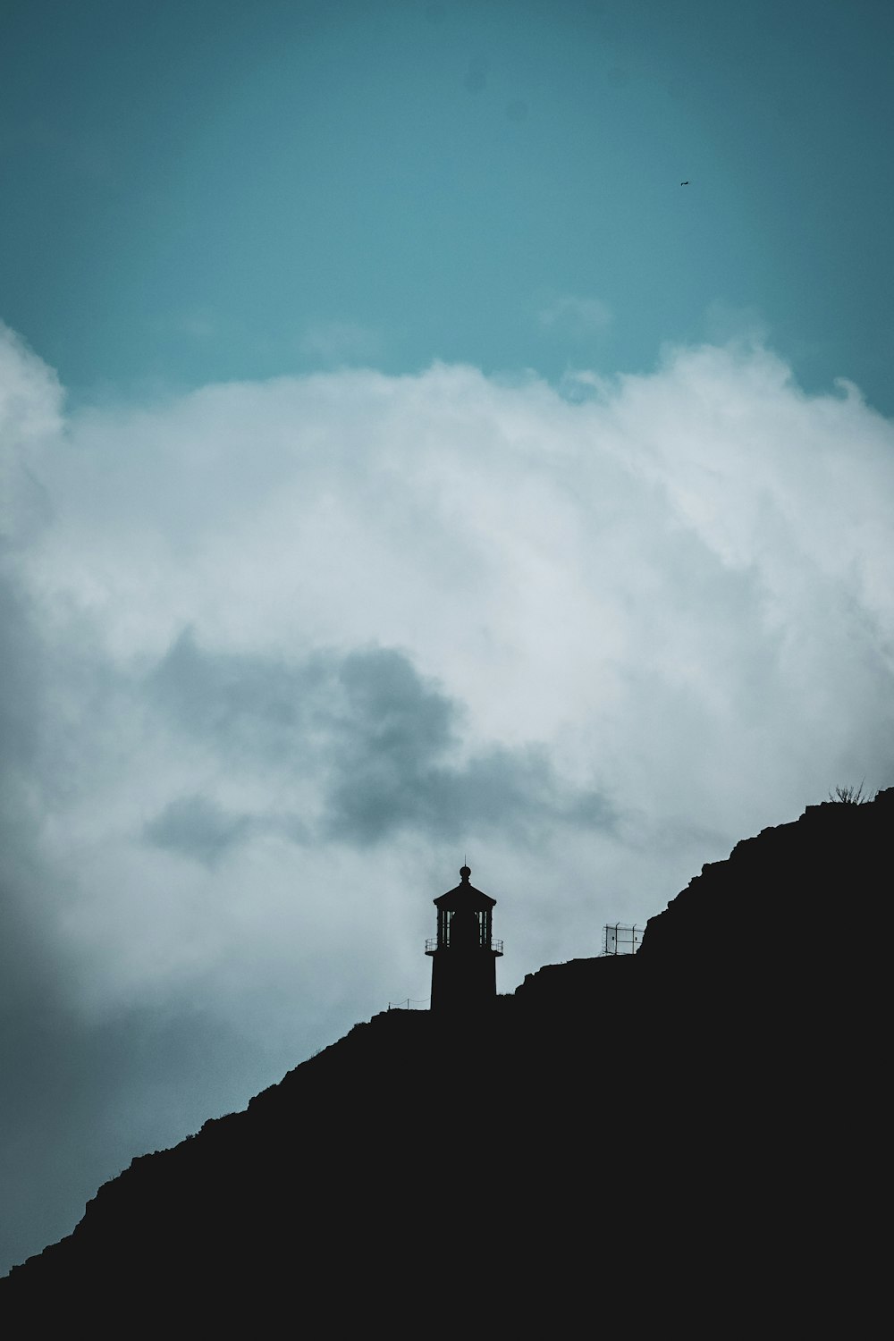 a clock tower on top of a hill under a cloudy sky