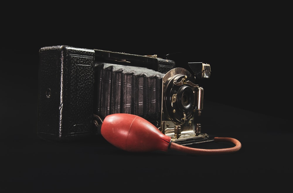 una vecchia macchina fotografica e un mouse di gomma rosso su sfondo nero