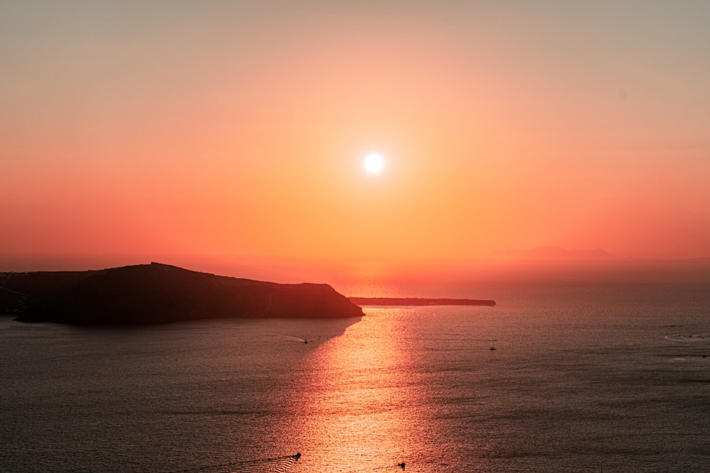 a large body of water with a sunset in the background