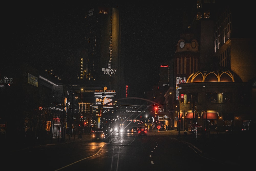 a city street at night with cars driving on it