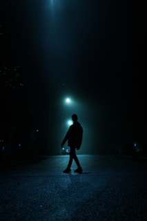 A shadowy figure walking down a deserted street at night, evoking mystery.