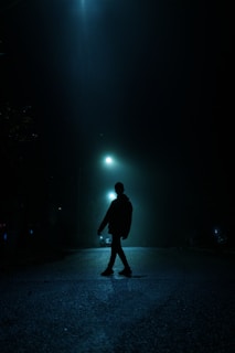 A shadowy figure walking down a deserted street at night, evoking mystery.