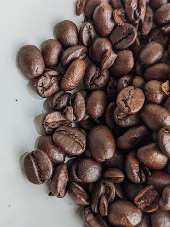 A close-up of roasted coffee beans with a rich, dark brown color and glossy texture.