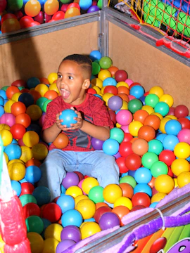 A joyful child playing with colorful therapy tools in a bright, gem-toned room.