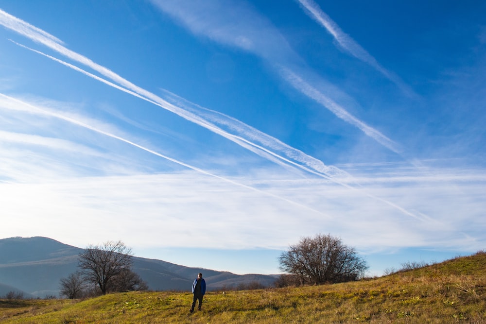 a man standing on top of a lush green hillside