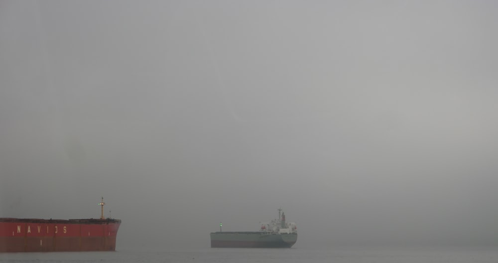 a large cargo ship and a smaller ship in the fog